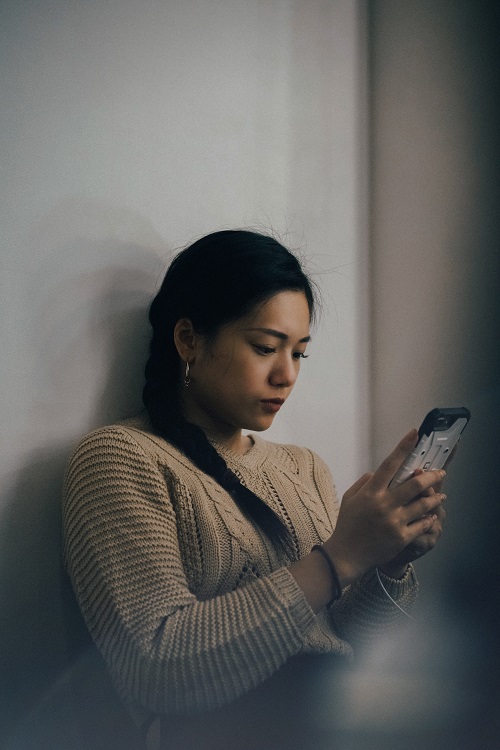 a woman looking at her phone while sitting on a couch using leadai